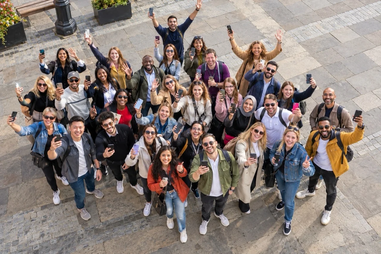 A large team smiling and waving their phones during a city day out
